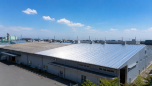 夏の日差しを反射する銀色の金属屋根を備えた工場