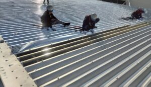 折板屋根にサーモバリア遮熱シートを施工した遮熱工事の様子と建物外観（工場・倉庫の暑さ対策）