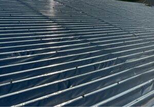 折板屋根にサーモバリア遮熱シートを施工した遮熱工事の様子と建物外観（工場・倉庫の暑さ対策）