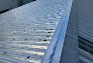 折板屋根にサーモバリア遮熱シートを施工した遮熱工事の様子と建物外観（工場・倉庫の暑さ対策）