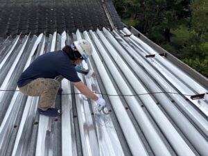 折板屋根の上に遮熱シートを直接貼り付けている施工中の様子